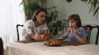 两个<strong>兄弟</strong>坐在厨房的桌子上，吃着牛角面包和卡布奇诺。 <strong>兄弟</strong>关系。